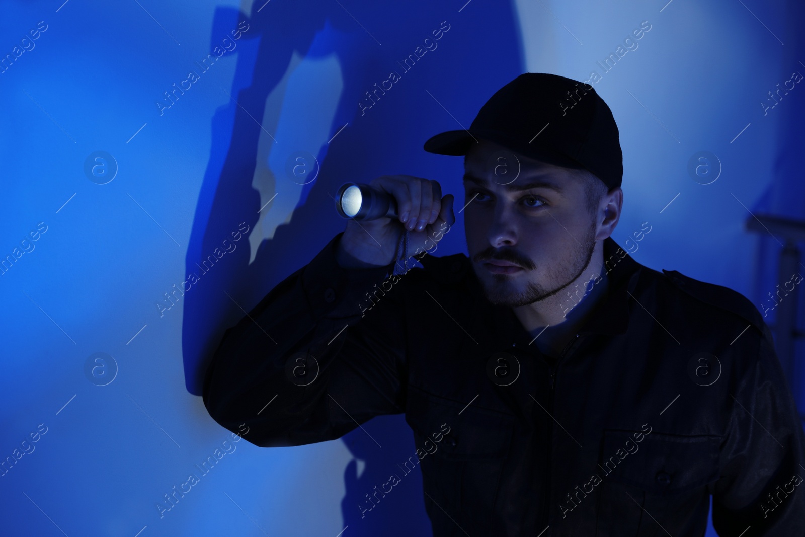 Photo of Male security guard with flashlight in dark room