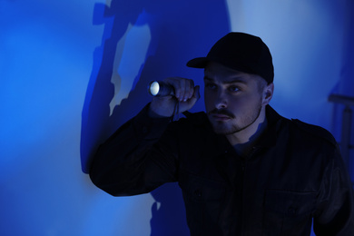 Photo of Male security guard with flashlight in dark room