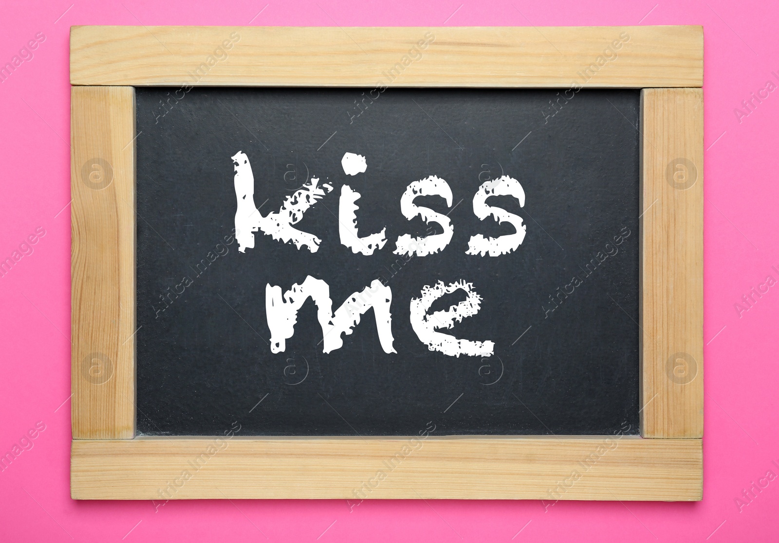Photo of Small chalkboard with phrase Kiss Me on pink background, top view