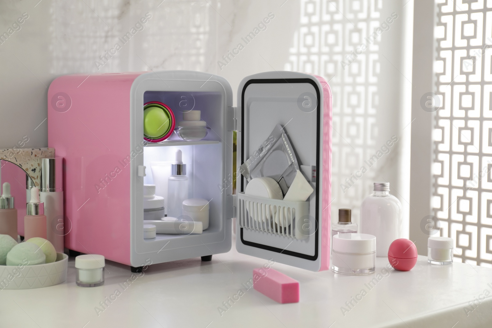 Photo of Cosmetics refrigerator and skin care products on white table indoors