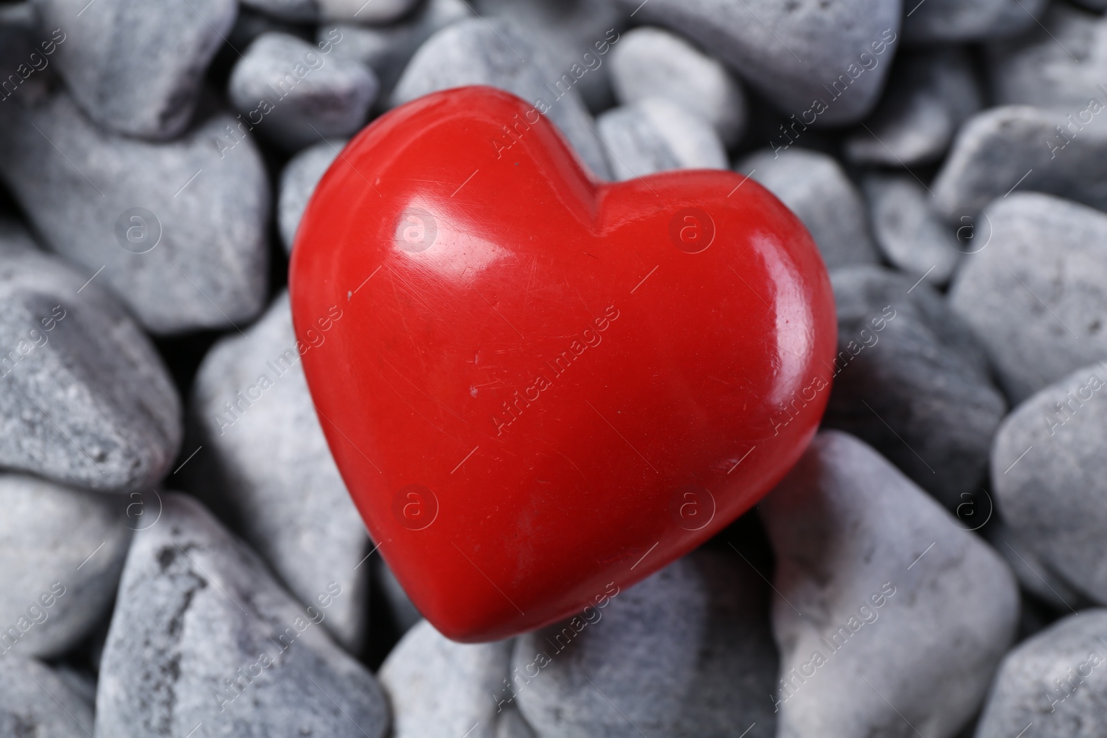 Photo of One red decorative heart on grey stones, closeup