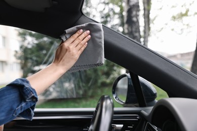 Photo of Woman wiping her modern car with rag, closeup