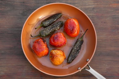 Photo of Frying pan with ingredients for salsa sauce on wooden table, top view