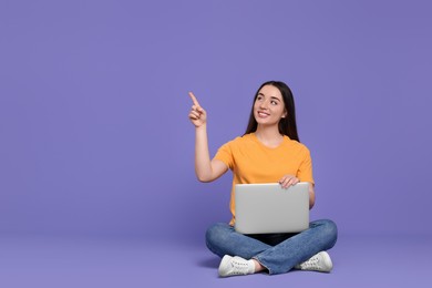 Photo of Smiling young woman with laptop on lilac background, space for text