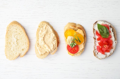 Photo of Delicious tomato bruschettas on white wooden background, flat lay