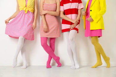 Women wearing colorful tights near white wall, closeup