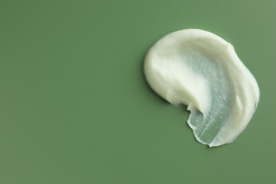 Photo of Sample of face scrub on green background, top view. Space for text