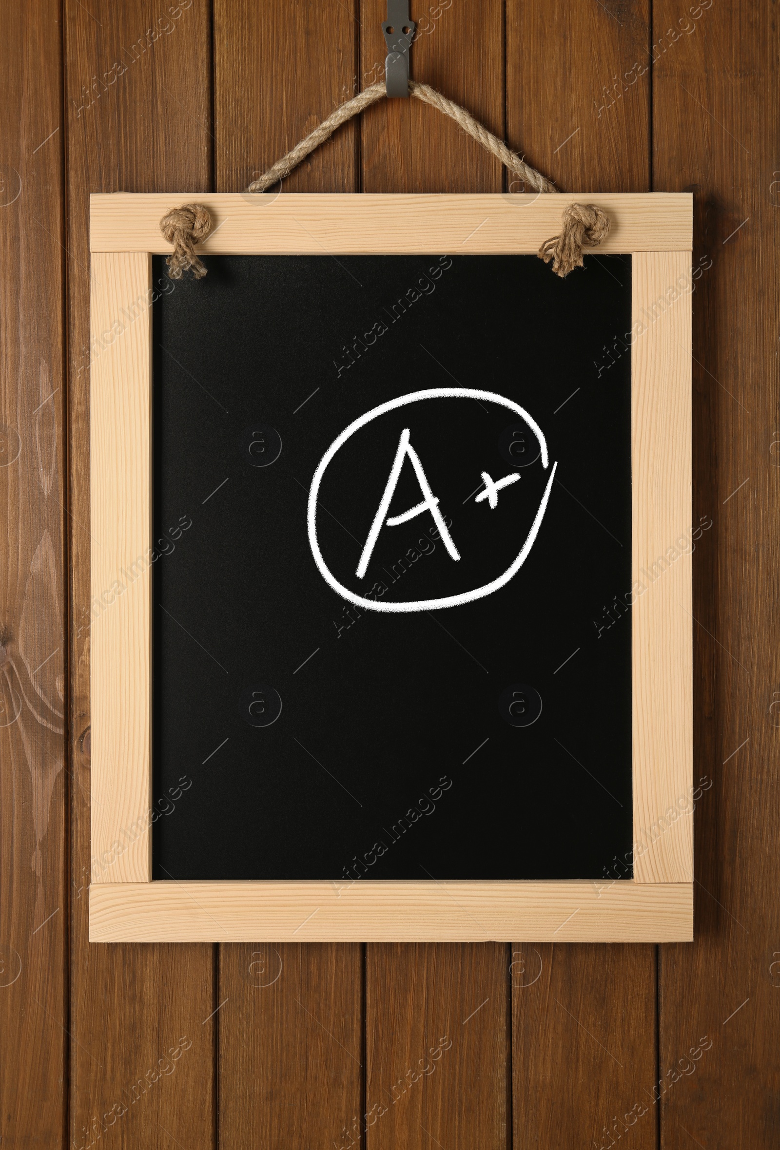 Image of School grade. Small blackboard with chalked letter A and plus symbol on wooden wall