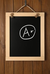 School grade. Small blackboard with chalked letter A and plus symbol on wooden wall