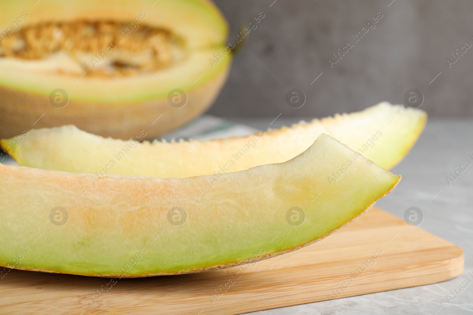 Photo of Slices of delicious ripe melon on grey marble table, closeup