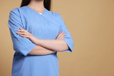 Photo of Nurse in medical uniform on light brown background, closeup. Space for text