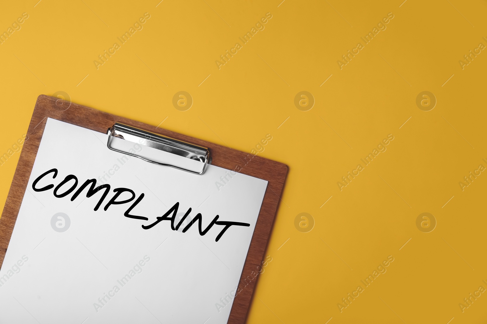 Image of Paper with word Complaints attached to clipboard on golden background, top view. Space for text
