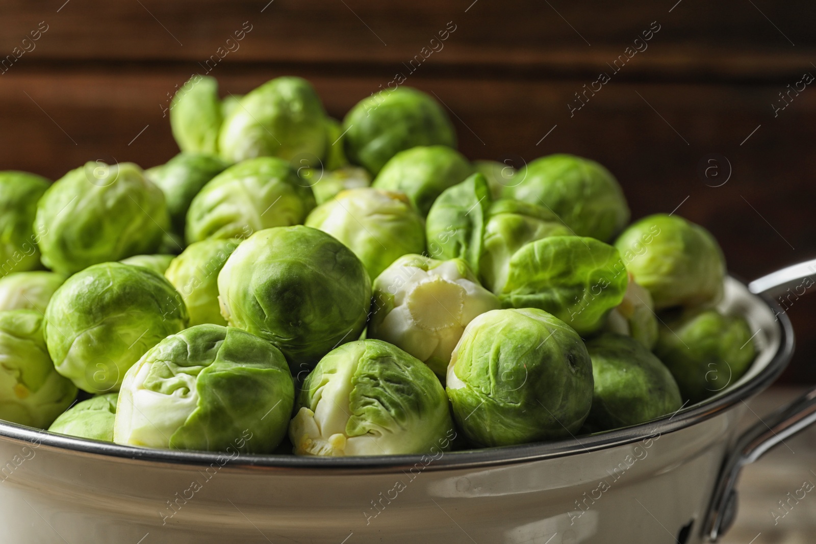 Photo of Colander with fresh Brussels sprouts on blurred background, closeup