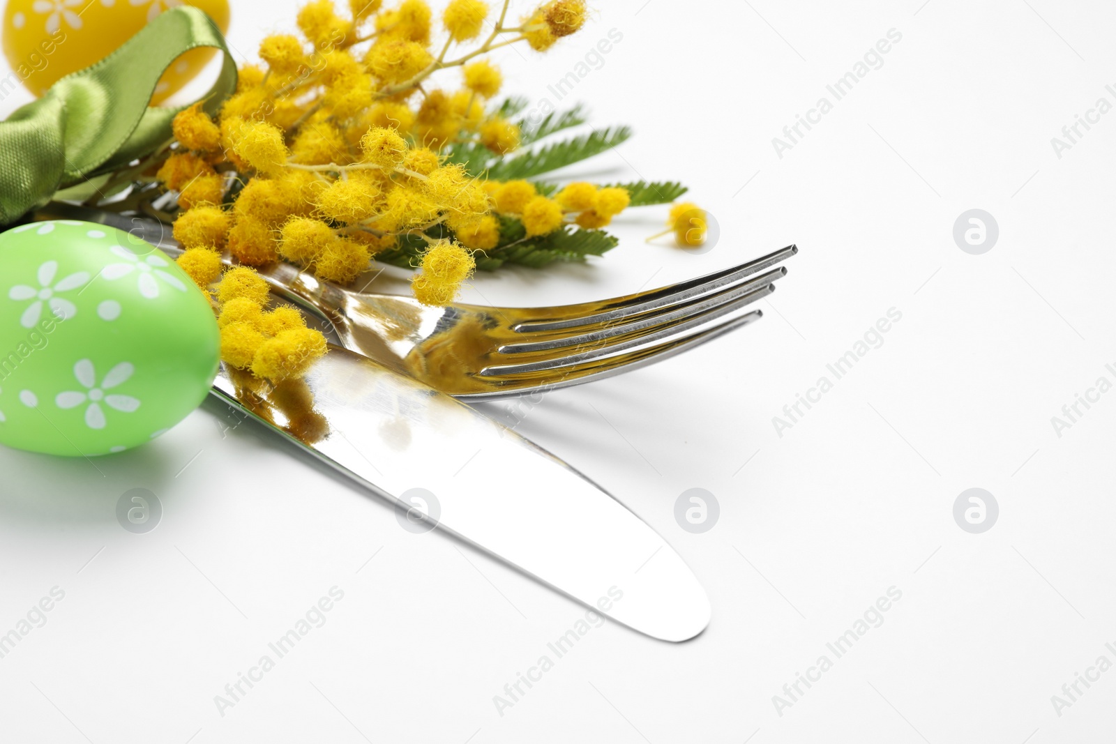 Photo of Cutlery set with floral decor for Easter celebration on white background, closeup