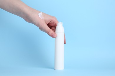 Woman with cream on light blue background, closeup