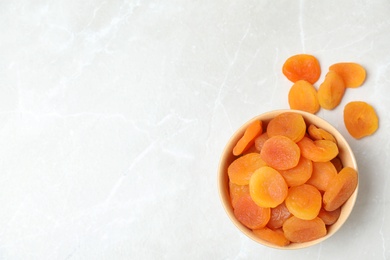 Photo of Bowl of apricots on grey background, top view with space for text. Dried fruit as healthy food