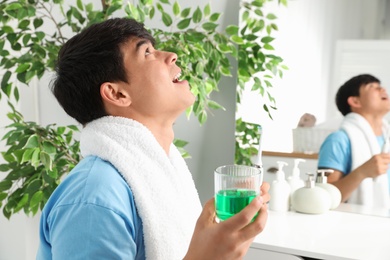 Photo of Man rinsing mouth with mouthwash in bathroom. Teeth care