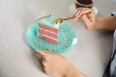 Photo of Woman eating fresh delicious birthday cake at table, closeup