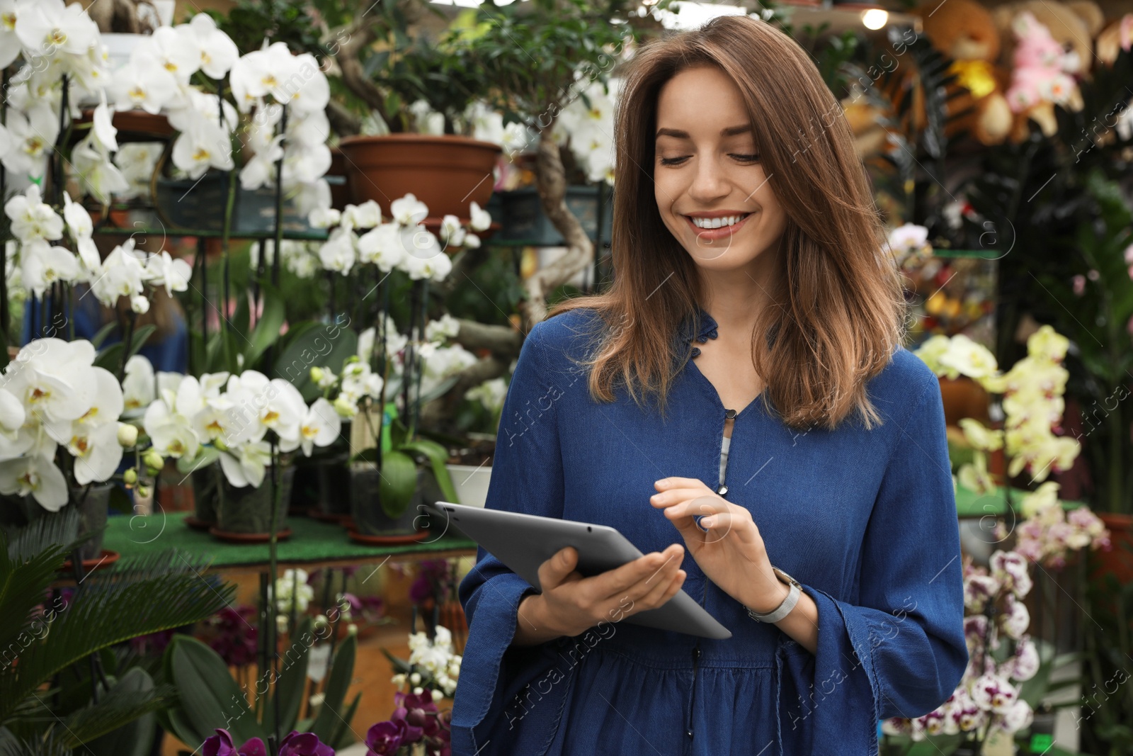 Photo of Young business owner with tablet in flower shop