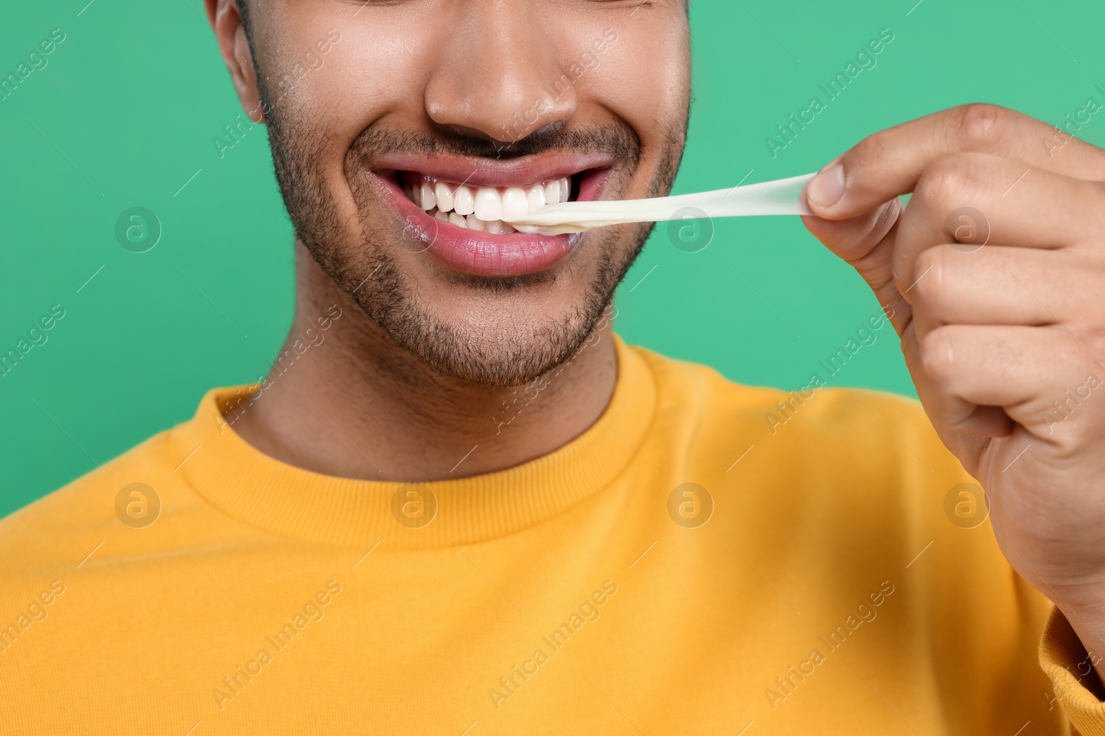 Photo of Happy man with bubble gum on green background, closeup