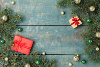 Photo of Flat lay composition with decorated fir branches and gifts on blue wooden background, space for text. Winter holidays