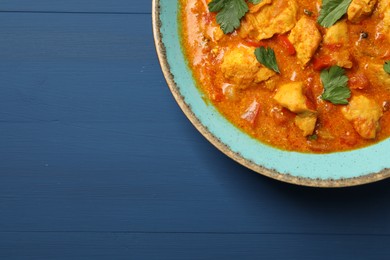 Photo of Delicious chicken curry on blue wooden table, top view. Space for text