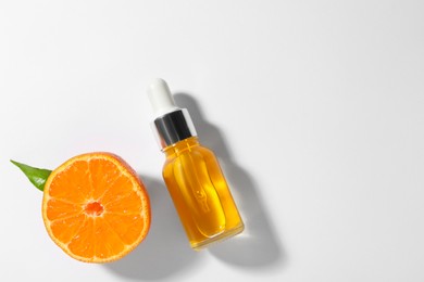 Photo of Aromatic tangerine essential oil in bottle and citrus fruit on white table, top view. Space for text