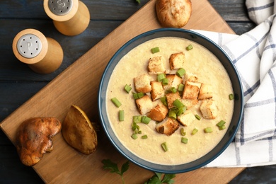 Flat lay composition with bowl of fresh homemade mushroom soup on wooden background