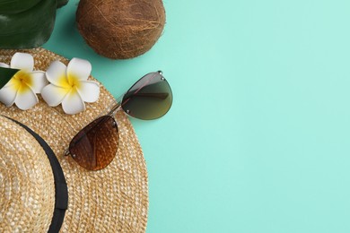 Photo of Stylish sunglasses, straw hat, coconut and beautiful plumeria flowers on turquoise background, flat lay. Space for text