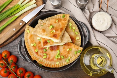 Delicious fried chebureki with cheese, green onion and ingredients on wooden table, flat lay
