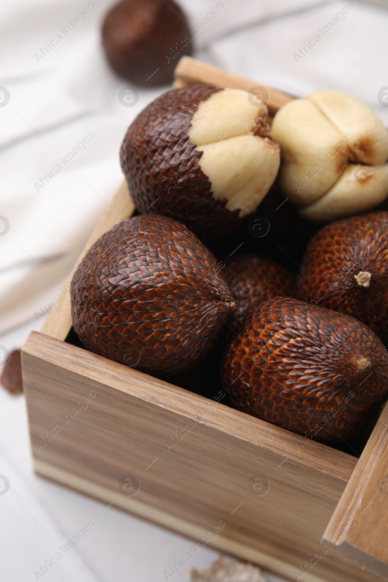 Photo of Wooden crate with fresh salak fruits on table, closeup