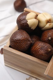 Wooden crate with fresh salak fruits on table, closeup