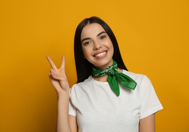 Young woman wearing stylish bandana on orange background