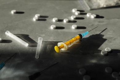 Photo of Syringe and drugs on grey textured table, closeup