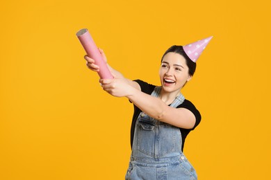 Photo of Young woman blowing up party popper on yellow background
