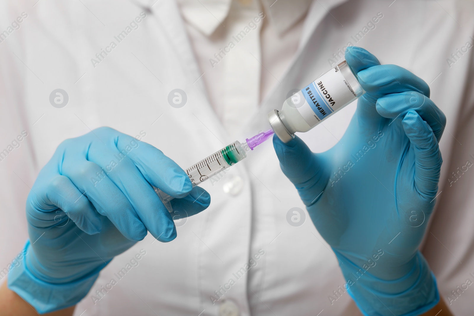 Photo of Doctor filling syringe with hepatitis vaccine from glass vial, closeup