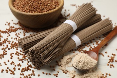 Photo of Uncooked buckwheat noodles (soba), flour and grains on white table