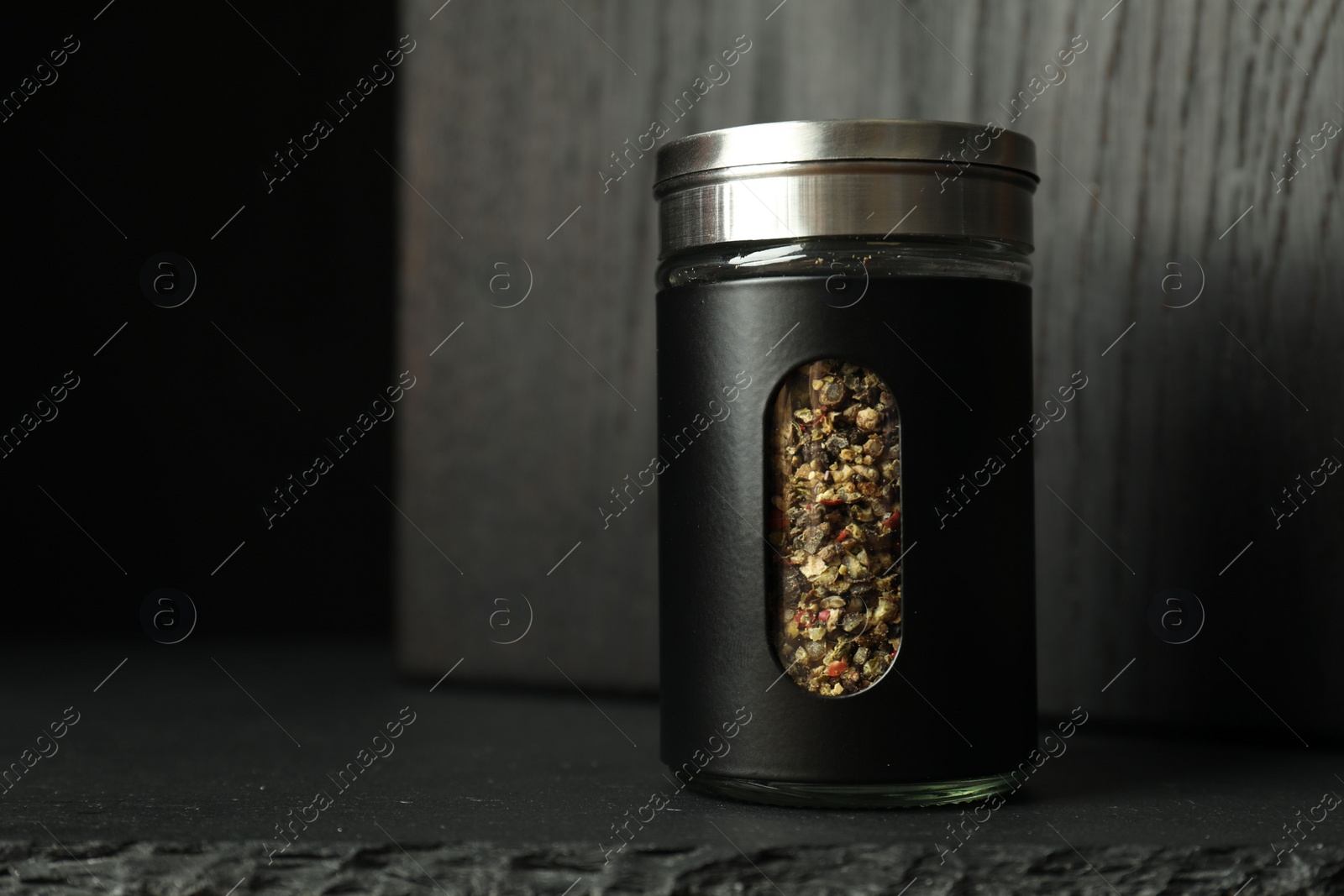 Photo of Pepper shaker on black table, space for text