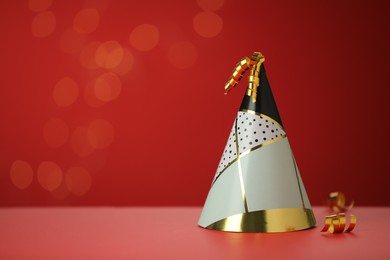 Photo of Beautiful party hat and serpentine streamers on red background, space for text