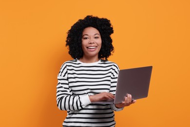 Photo of Happy young woman with laptop on orange background