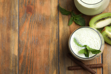 Photo of Tasty milk shake with kiwi on wooden table, flat lay. Space for text