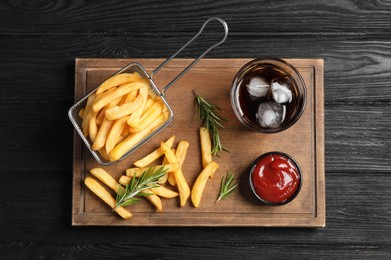 Tasty french fries, ketchup and soda drink on dark wooden table, top view