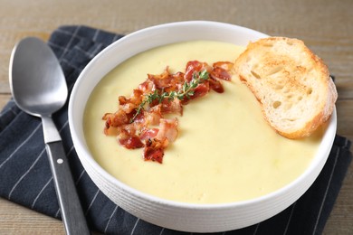 Tasty potato soup with bacon and rosemary in bowl served on wooden table