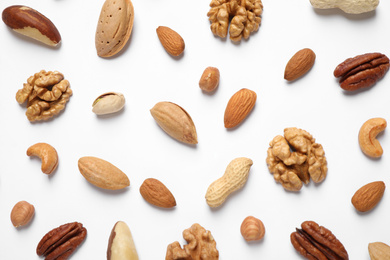 Different delicious nuts on white background, flat lay