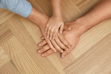 Happy family holding hands on wooden background, top view