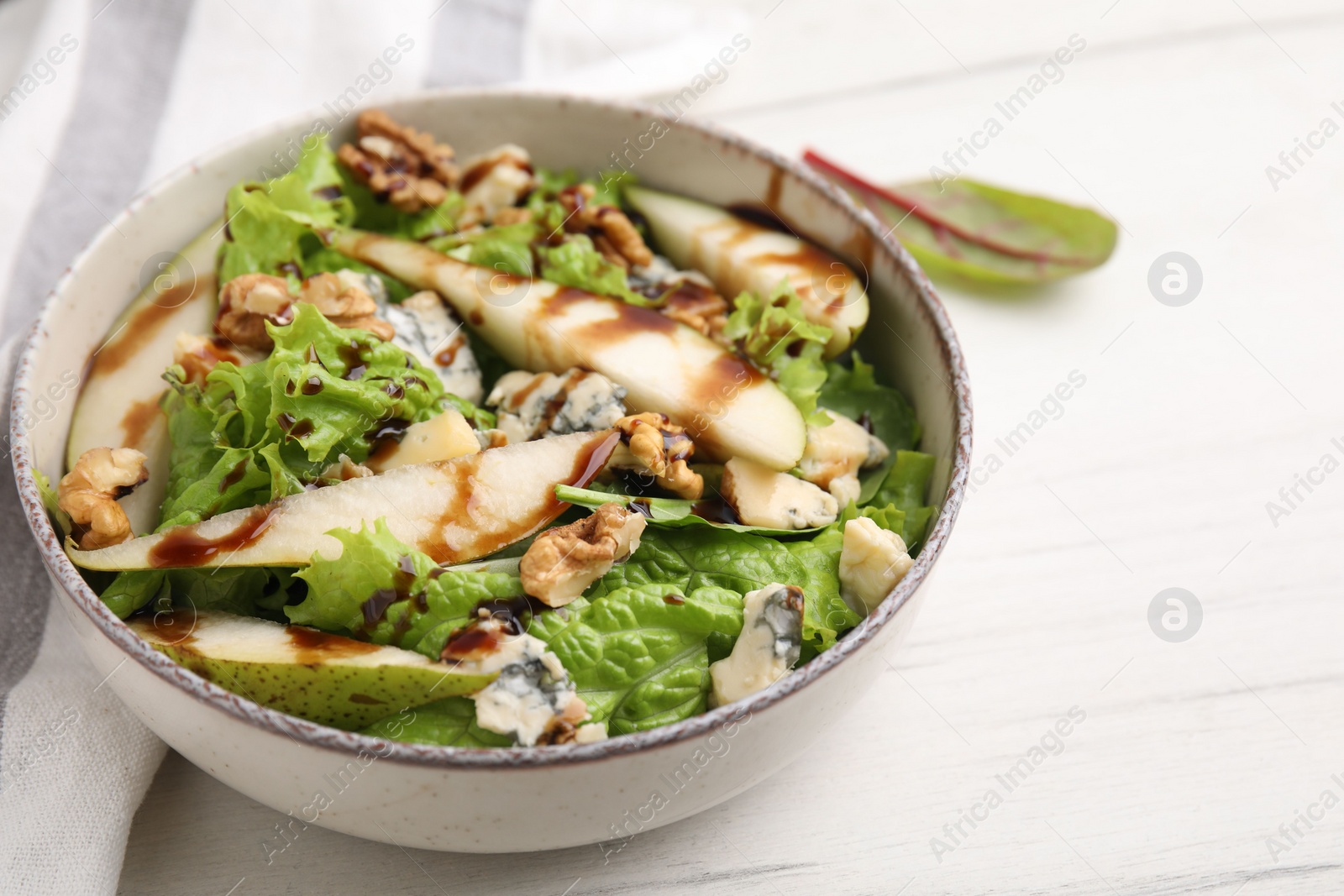 Photo of Delicious pear salad with sauce in bowl on light table, closeup. Space for text