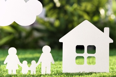 Paper cutout of family and house on fresh grass. Life insurance concept