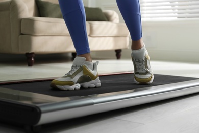 Photo of Woman training on walking treadmill at home, closeup