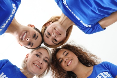 Photo of Team of volunteers joined in circle on light background, bottom view