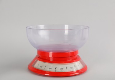Kitchen scale with plastic bowl on light grey background
